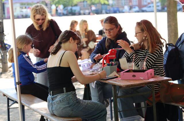 Kinder / Jugendliche sitzen am Tisch, basteln und malen.