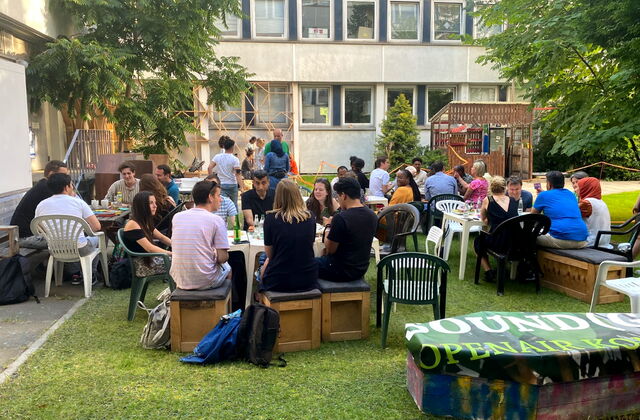 Menschen an Tischen sitzen und essen und erzählen. Draußen, fröhliche Menschen mit verschiedenen Hautfarben.