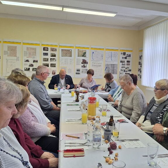 Gedeckter Tisch in T-Form. Noziten auf dem Tisch an dem ältere Menschen sitzen.
