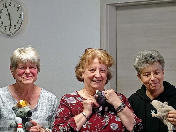 3  fröhliche Frauen mit Plüsch-Ratten in den Händen lächeln in die Kamera.