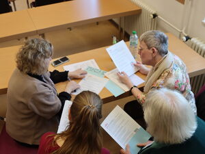 4 Personen lesen und bearbeiten Unterlagen an einem Tisch.