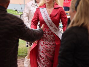 Frau in roten pompösen Kleid mit Schärpe: Baumblütenkönigin 2026. Sie ist blond und trägt eine Krone.