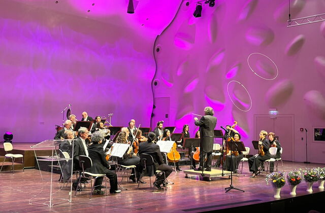 Orchester mit Dirigent auf der Bühne.
