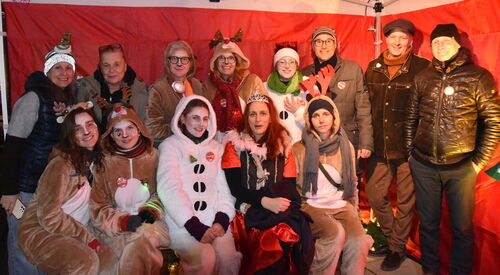 Gruppenbild: 13 Personen, einige verkleidet als Rentier, Schneemann und Fee. Alle sehen sehr fröhlich in die Kamera.