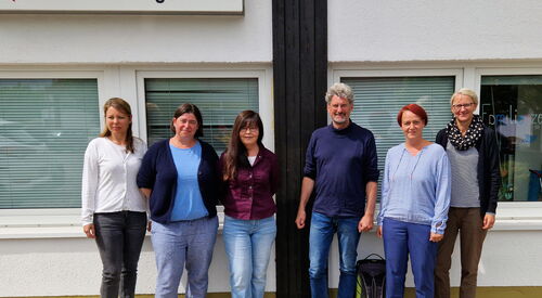 Gruppenbild. 5 Frauen und ein Mann vor einem Gebäude. Oben ein großes Schild am Gebäude angebracht. AWO-Logo        Haus Belzig Beratungsstelle