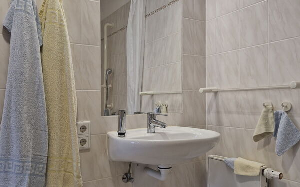 Badezimmer. Waschbecken, großer Spiegel darüber. Links daneben zwei Handtücher.