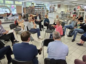 Ein großer Raum, 21 Menschen sitzen in Stuhlkreisen. In der Mitte wird diskutiert.