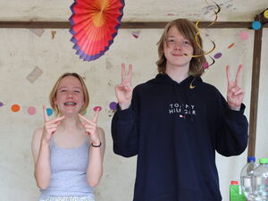 2 Kinder / Jugendliche stehen nebeneinander und grinsen in die Kamera.