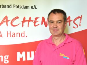 Portrait: Mann mit kurzen dunklen Haaren und einem schmalen Gesicht. Er trägt ein pinkes Poloshirt mit dem Aufdruck: Freie Demokraten FDP.