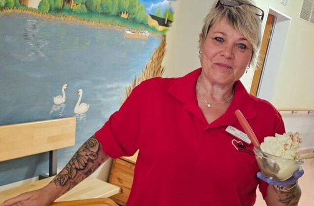 Frau im roten T-Shirt hält Eisbecher mit Sahne in der Hand.