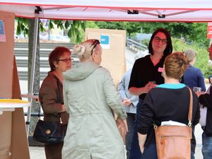 4 Frauen und ein Mann stehen unter den AWO Pavilon und unterhalten sich. Einige haben Getränke in der Hand.