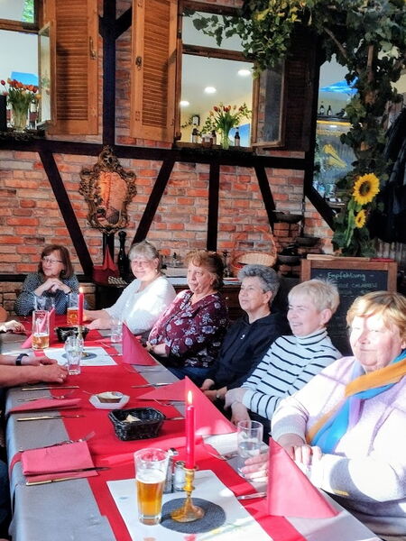 Restaurant. Langer gedeckter Tisch mit rotem Läufer und Kerzen. Menschen sitzen am Tisch.