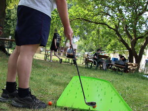 Ein Mann mit rotem Base Cape beim Mini-Golf.