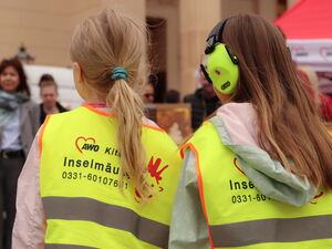 Kinder von hinten in gelben Warnwesten der AWO Kita Inselmäuse.