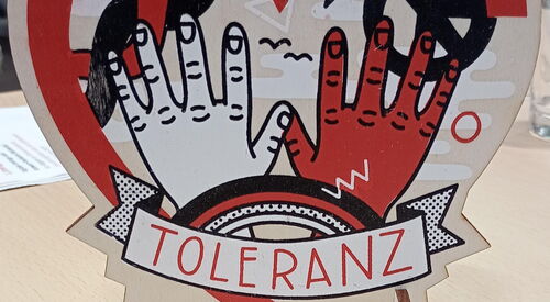 AWO Herz-Aufsteller für Tisch. Mit dem Wort TOLERANZ und Bildern, wie Hände, Peace Symbol, Regenbogen