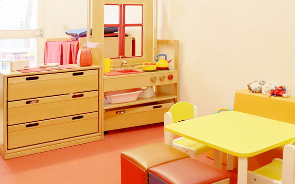 Kinderküche aus Holz, mit Herd, Spüle, Tisch und zwei Stühle.