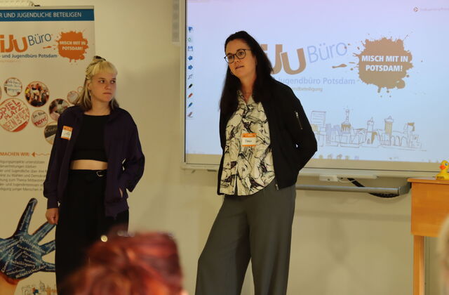 "Misch mit in Potsdam" Präsentation. 2 Frauen stehen vor den Teilnehmenden.