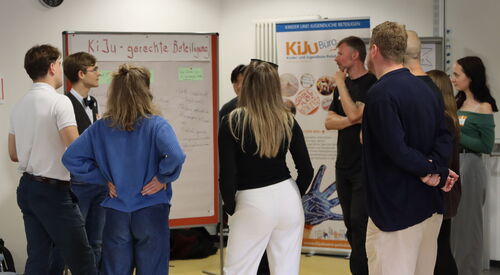Kleingruppe steht um Flipchart zum Thema Kinder und Jugendgerechte Beteiligung.