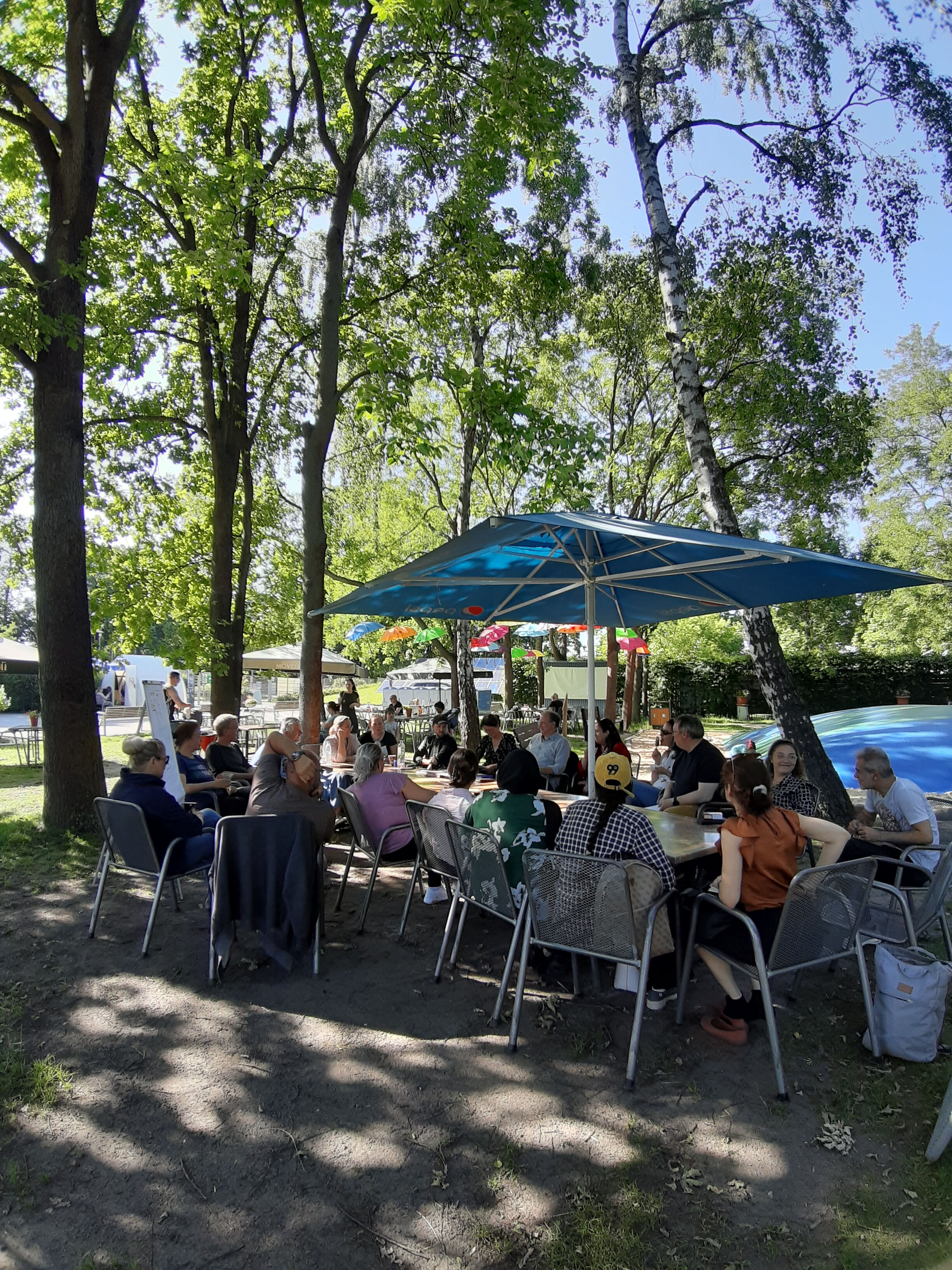 das Foto zeigt eine Gruppe von Menschen, die ein Meeting im Freien abhalten
