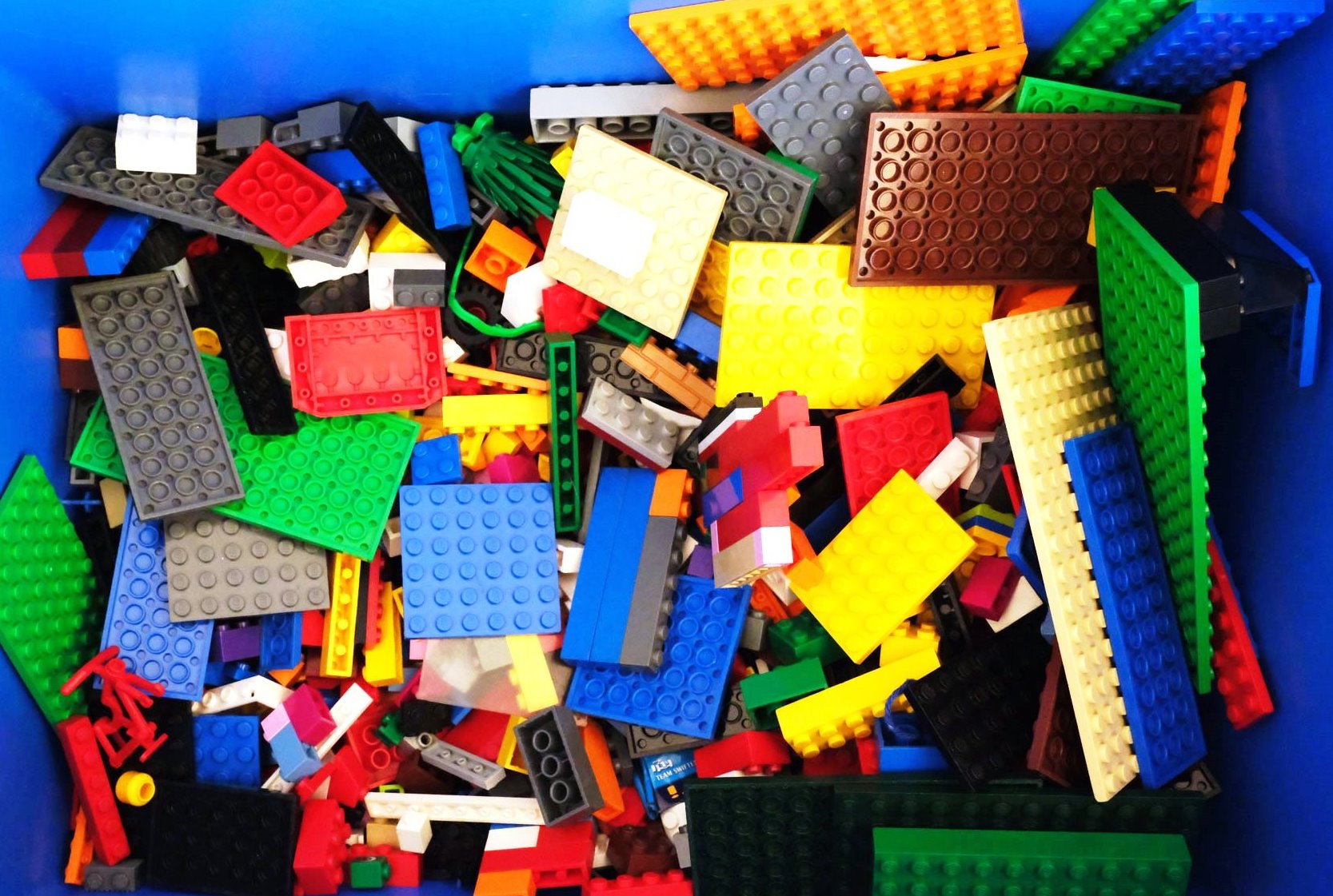 Blick in eine blaue Kiste gefüllt mit Lego-Bausteinen.