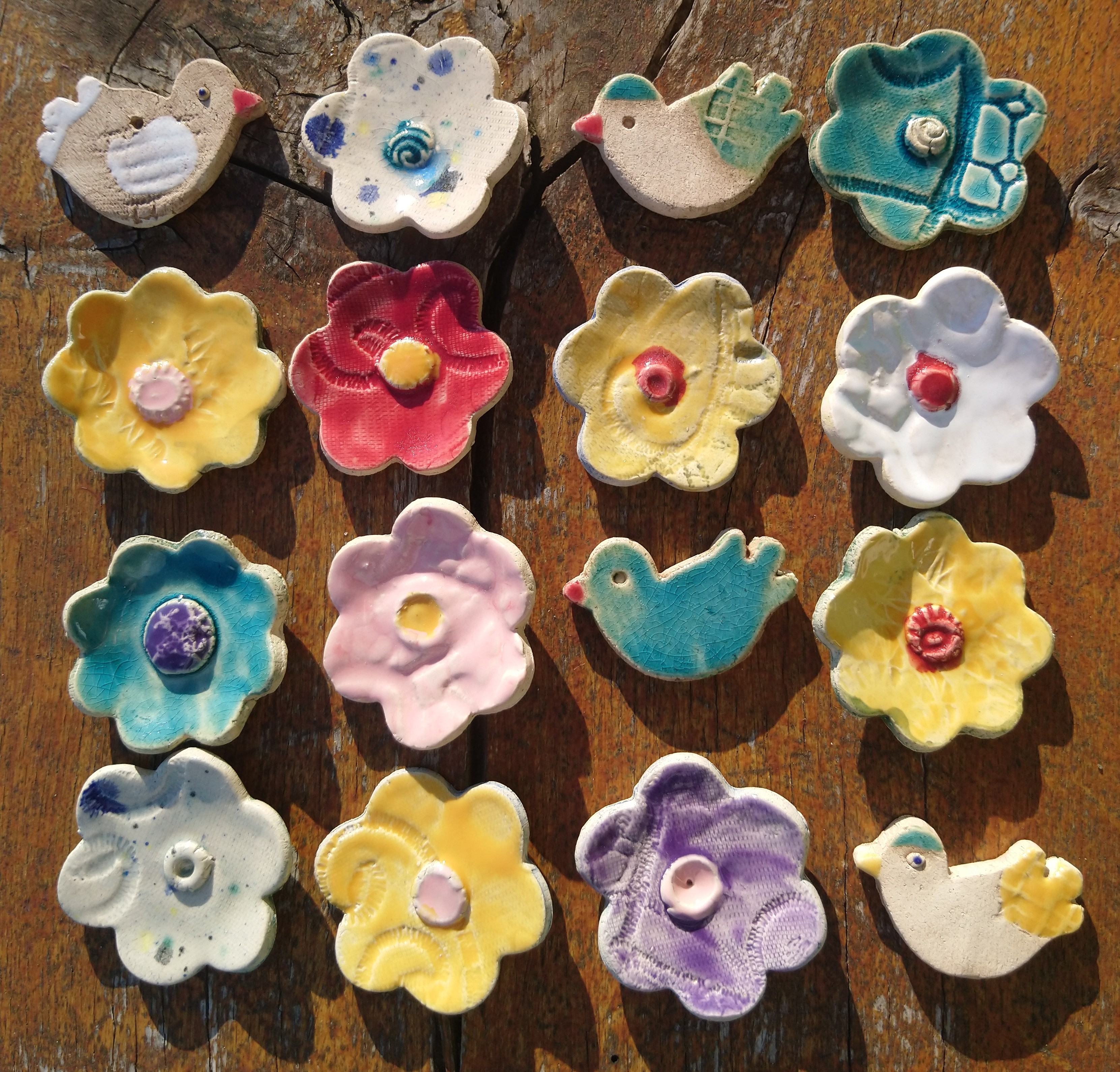 Das Bild zeigt kleine, bunte selbstgetöpferte Blumen und Vögel