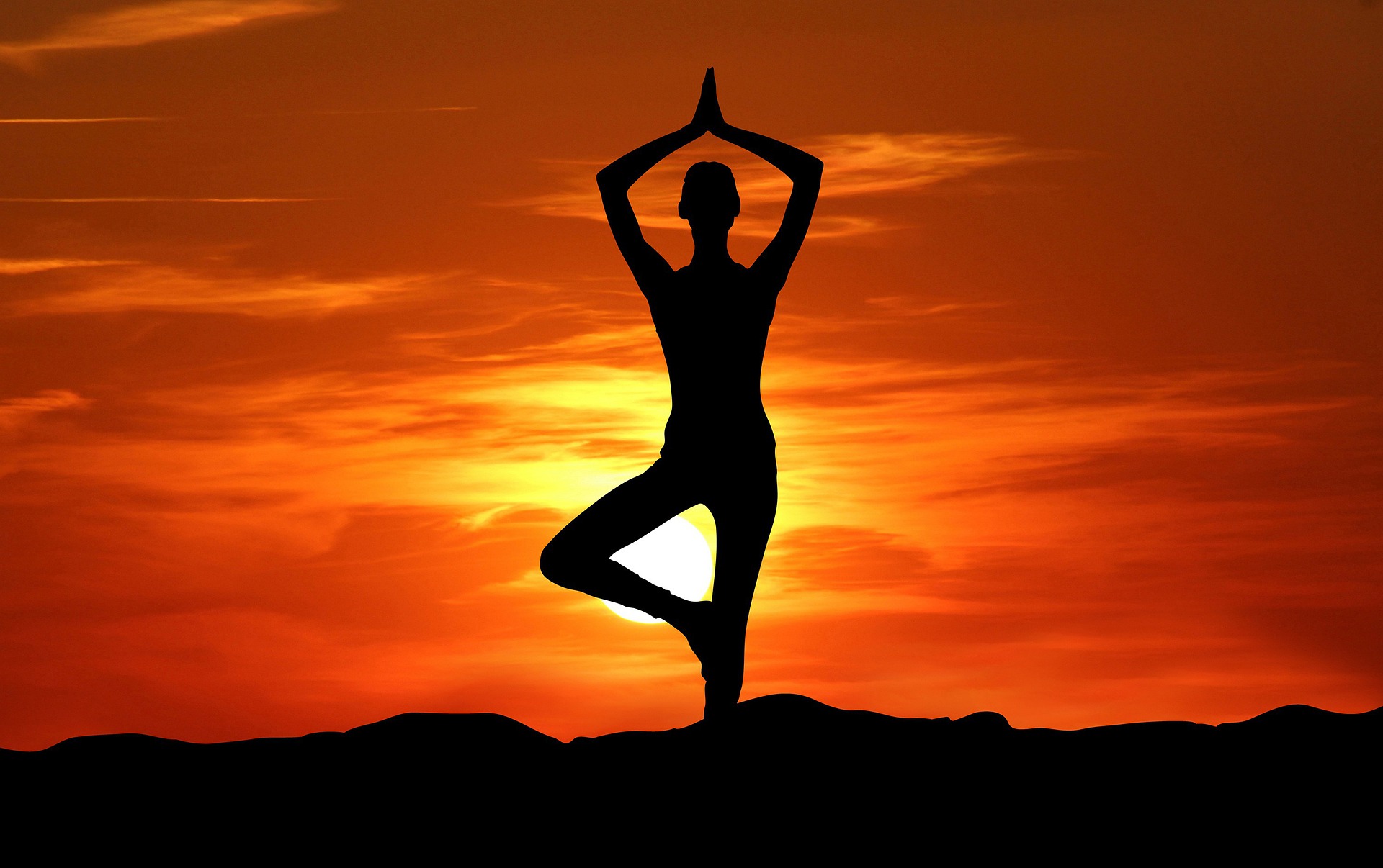Eine Frau in Yoga-Pose vor dem Sonnenaufgang