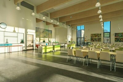 Aula. Großer lichtdurchfluteter Raum mit vielen Stühlen.