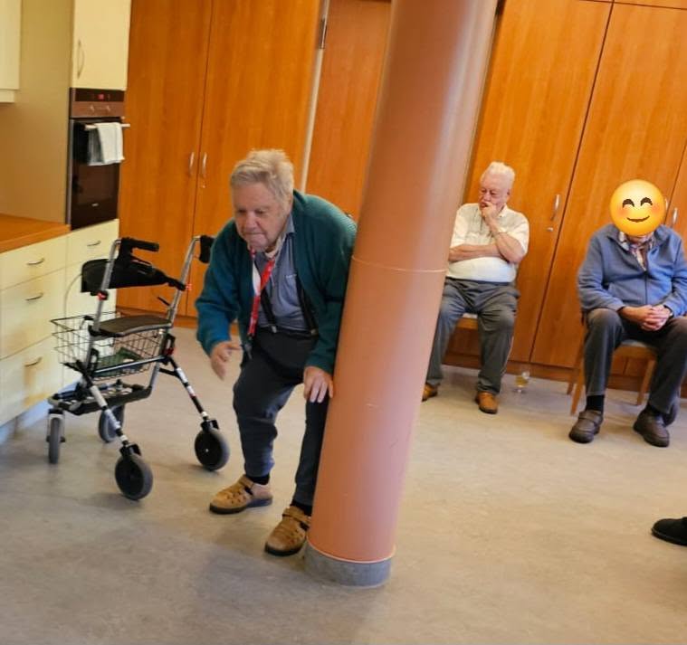 Ältere Person steht gebückt neben einem Rollator.