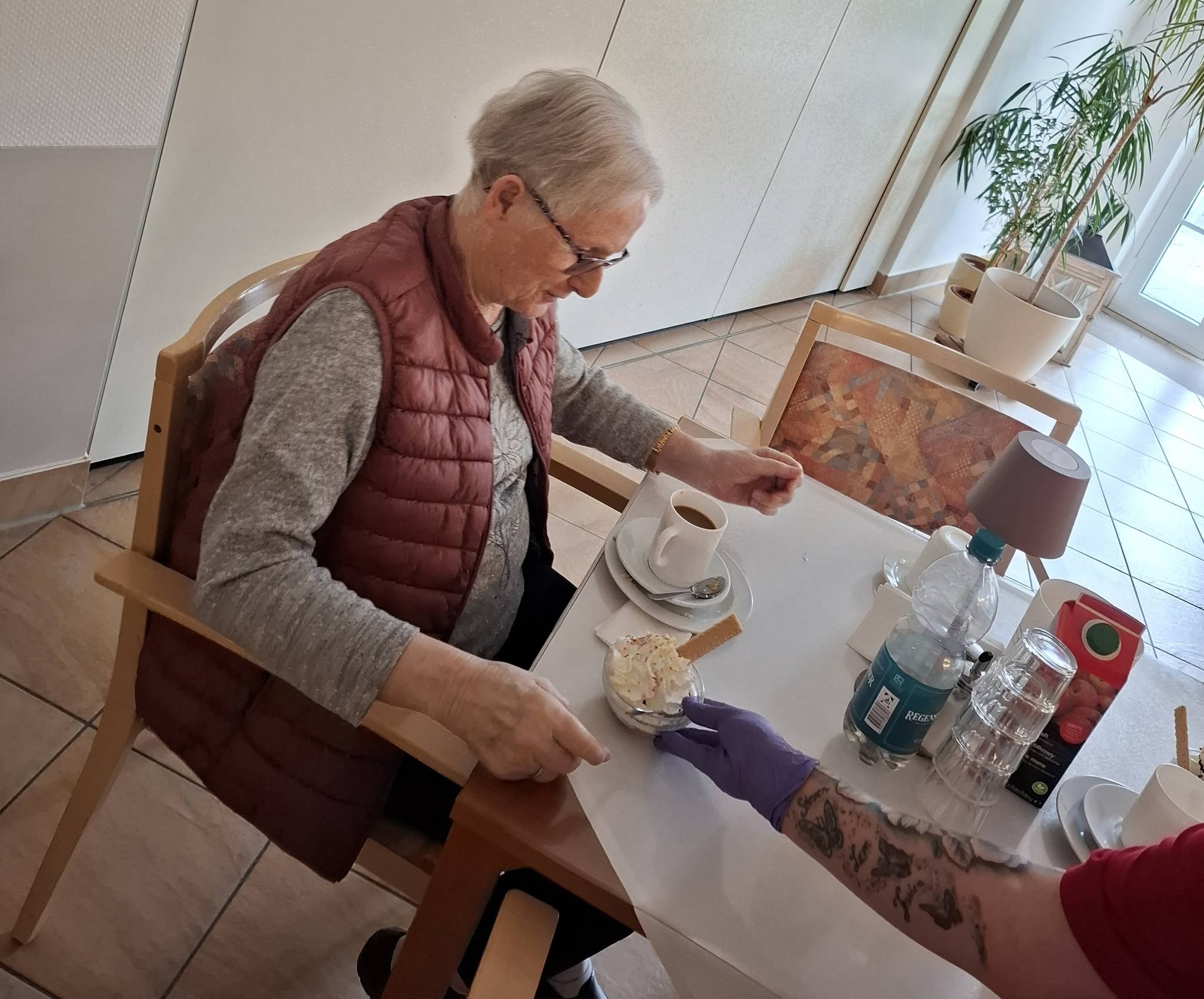 Seniorin bekommt Kaffee und Eis serviert.