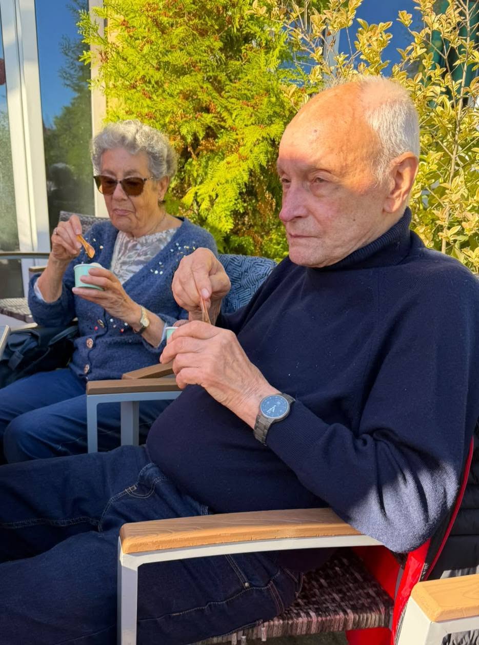 Senioren sitzen in der Sonne und essen Eis.