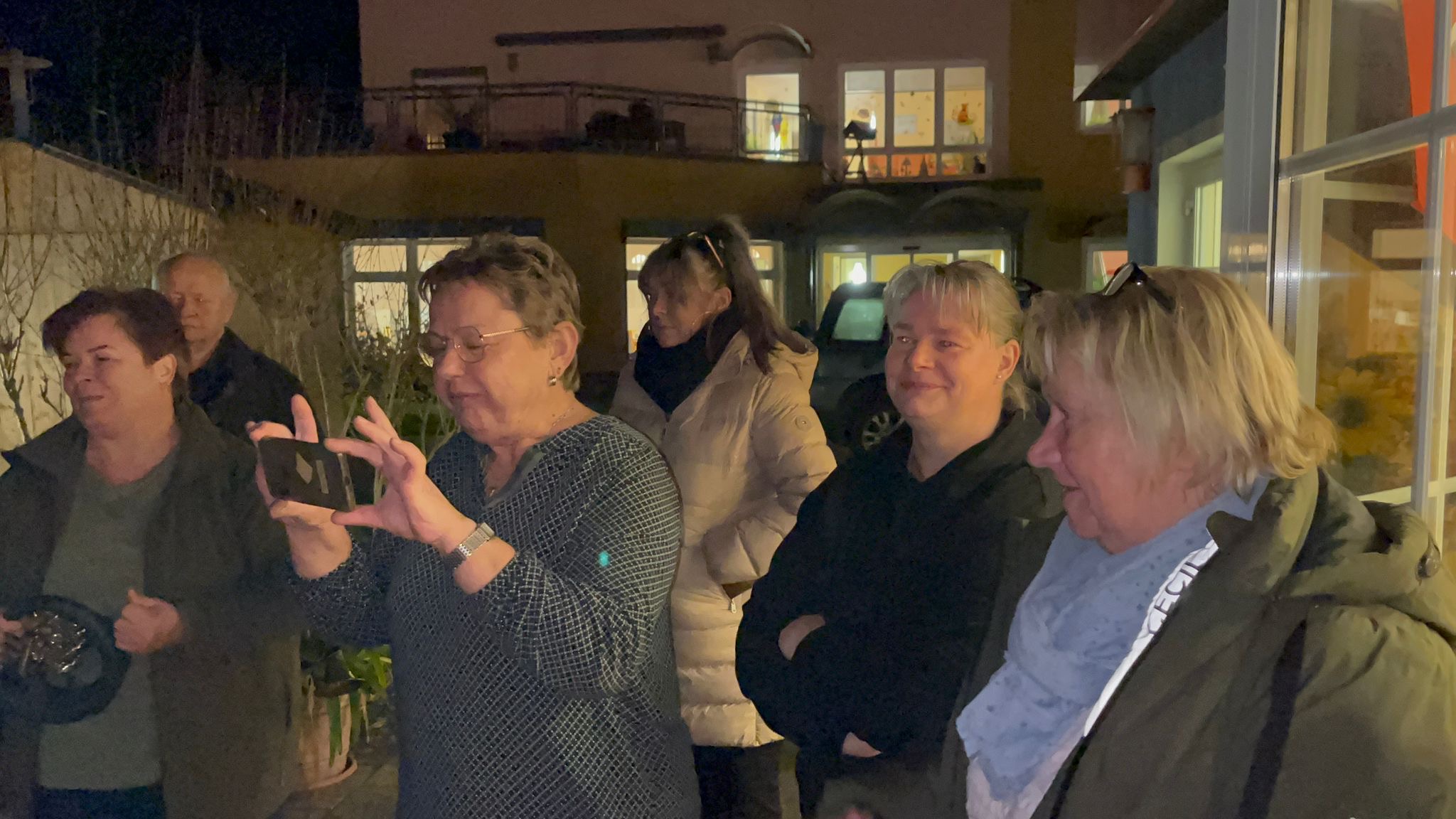 Personen die sich erfreuen und eine Dame die mit ihrem Handy Bilder macht