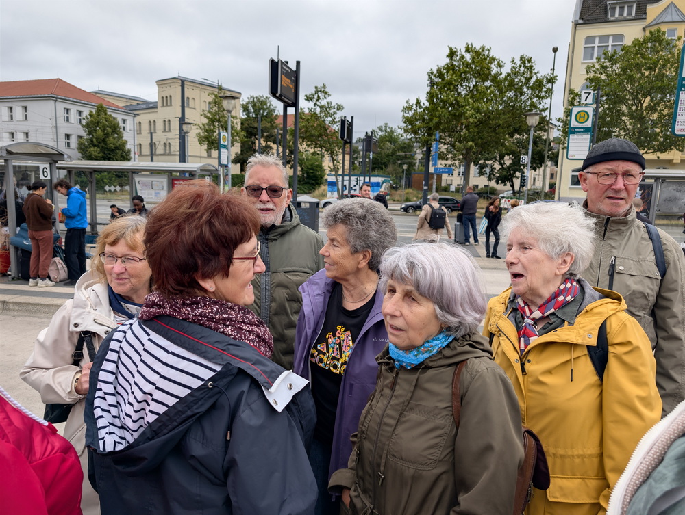 Wandergruppe an einer Haltestelle mit mehreren Bussteigen.