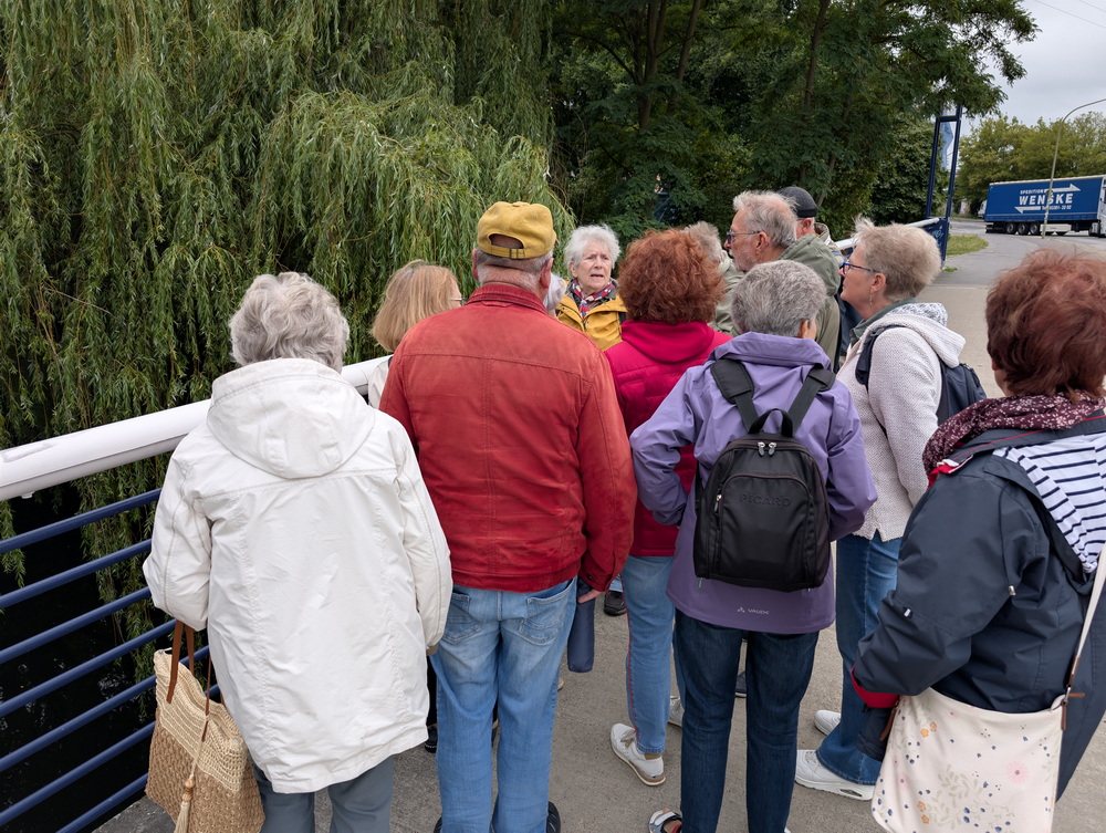 Wandergruppe auf einer Brücke, rechts ist eine Straße.
