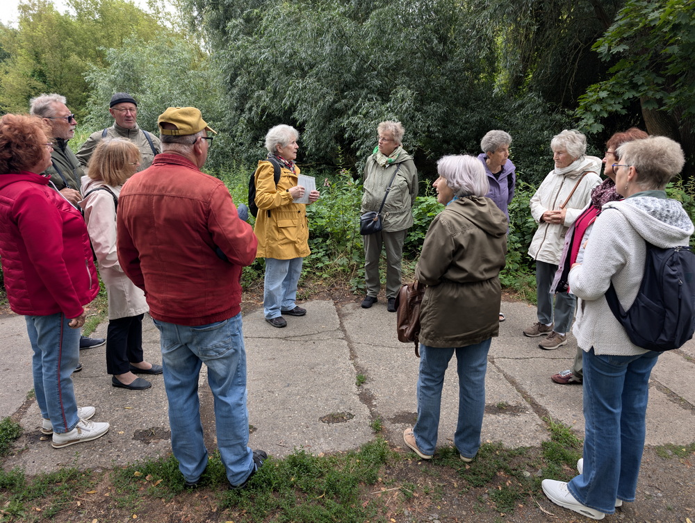 Wandergruppe hat Kreis gebildet und hört der Führerin zu.