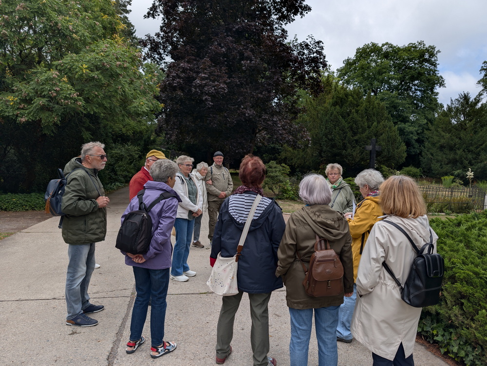Wandergruppe steht im großen Kreis, während Führerin etwas zeigt.