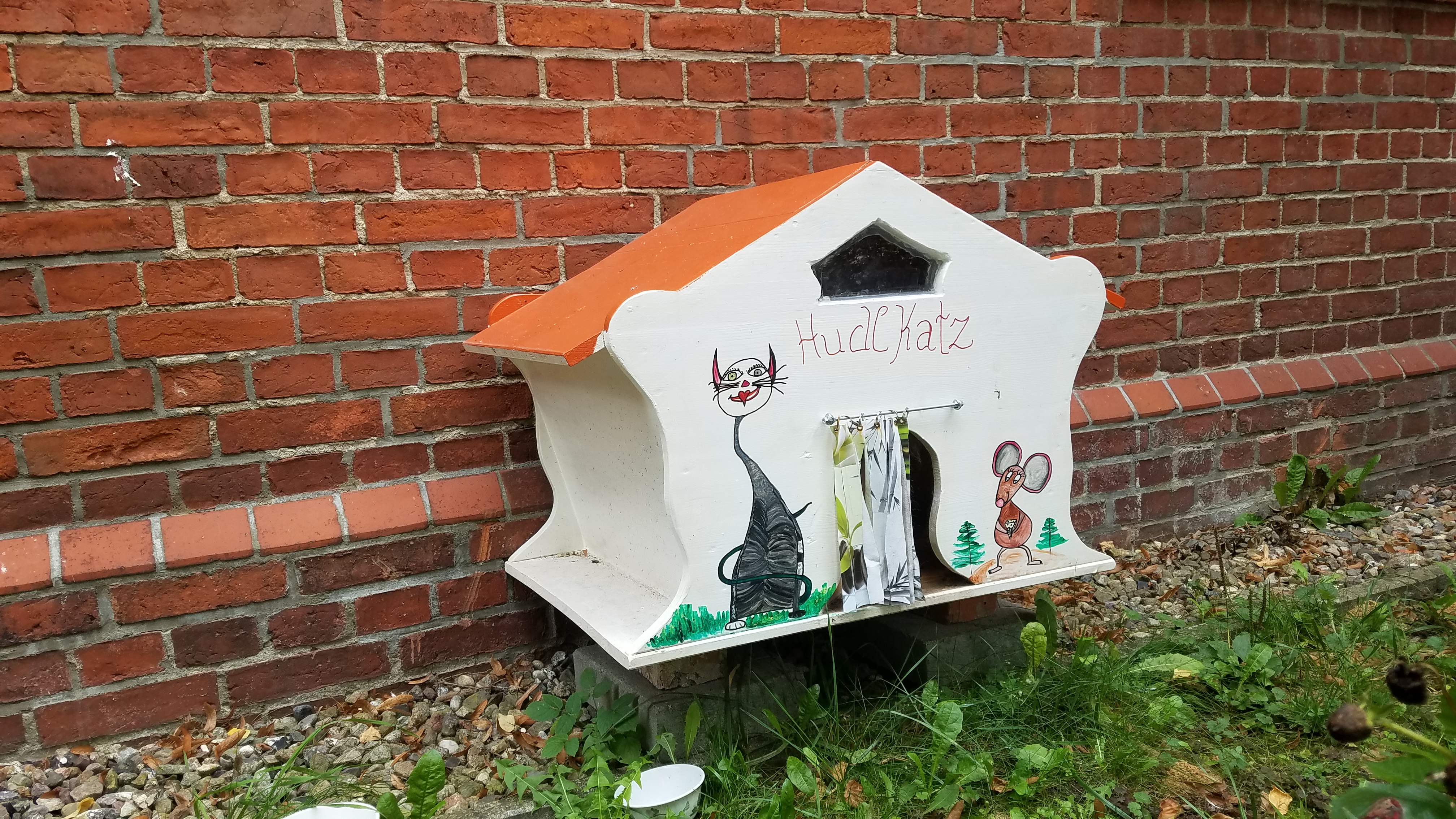 Ein selbst gebautes Katzenhaus an einer Häuserwand